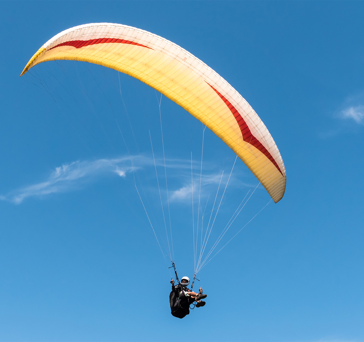 Paraglider flying in blue sky.